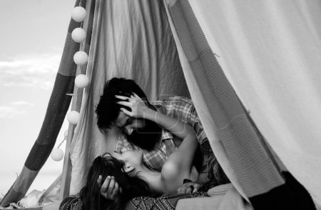 Téléchargez les photos : Couple romantique camper et embrasser en tente le jour de l'été. Couple sexy sensuel sur pique-nique, style de vie de camping avec petite amie - en image libre de droit