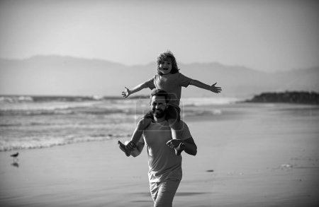Foto de Un niño pequeño con papá cargándolo en hombros. Padre llevando a su hijo de vuelta afuera. Concepto de familia amigable y de vacaciones de verano - Imagen libre de derechos