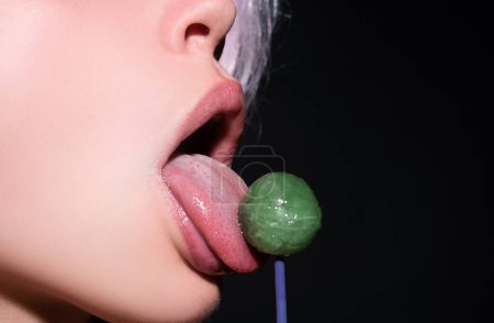 Photo for Lollipop in woman mouth, red lipstick. Woman licking a red shiny lollipop. Close up. Sexy woman with lollipop in sexy mouth - Royalty Free Image