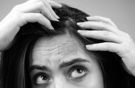 Téléchargez les photos : Gros plan de la femme examinant son cuir chevelu et ses cheveux, perte de cheveux sur la ligne des cheveux ou problème de cuir chevelu sec - en image libre de droit