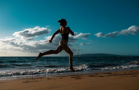 Foto de Mujer corriendo a lo largo del océano surf junto a la piscina de agua para mantenerse en forma y la salud. Mujer fitness, ejercicio de jogging y actividad deportiva en vacaciones de verano - Imagen libre de derechos
