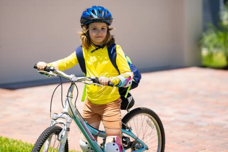 Foto de Un niño pequeño monta en bicicleta en el parque. Chico en bicicleta. Feliz niño sonriente en casco montando una bicicleta. El chico empieza a andar en bicicleta. Deportiva bicicleta de niño montar en bicicleta. bicicleta para niños - Imagen libre de derechos