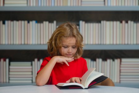 Foto de Día del conocimiento. Alumno de un niño leyendo un libro en una librería o biblioteca escolar. Estudio para niños leer - Imagen libre de derechos