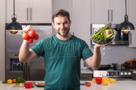 Photo for Portrait of handsome man in kitchen. Young man preparing delicious and healthy food in home kitchen. Man with recipe cooking vegetable salad in kitchen. Food vegetables ready to cook. Healthy food - Royalty Free Image