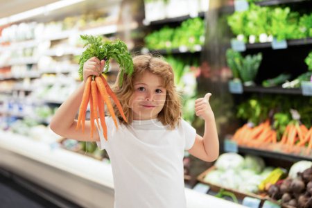Téléchargez les photos : Enfant choisissant des fruits et légumes en magasin alimentaire. Les enfants au marché des fruits et légumes. Ventes, réductions et achats. Garçon mignon tenir des légumes et des fruits. Achats d'enfants légumes et fruits - en image libre de droit