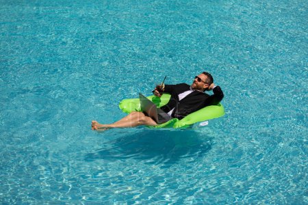 Photo for Funny business man in a business suit works for a laptop standing in the water in pool. Remote work. Crazy freelancer. Business and summer. Business man working online with computer laptop in pool - Royalty Free Image