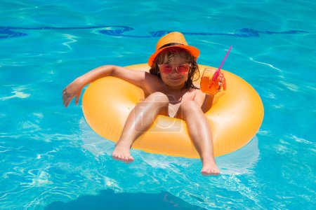Foto de Un chico flotando en la piscina. Niño relajante en la piscina, beber cóctel de verano. Vacaciones de verano para niños. Niños flotando en la piscina de agua. Niños jugando y ocio activo, concepto de piscina - Imagen libre de derechos