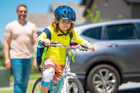 Photo for Father and son in bike helmet for learning to ride bicycle at park. Father helping son cycling. Father and son on the bicycle on summer day. Little son trying to ride bike with father. Fathers day - Royalty Free Image