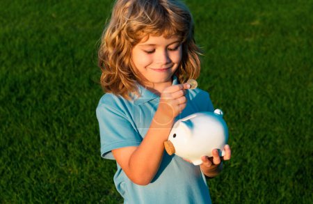 Photo for Little boy holding piggy bank and smiling. Portrait of child boy holding piggybank. Saving money concept. Cheerful happy child with is full piggybank - Royalty Free Image
