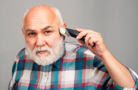 Hombre maduro con cortador de pelo. Viejo hombre calvo cortador de pelo, calvicie madura y concepto de pérdida de cabello
