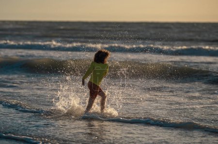 Photo for Child running and playing on tropical beach in summer day. Kid enjoy outdoor activity lifestyle. Summer vacation at the sea. Little boy running on beach at sunset. Kids on summer holiday vacation - Royalty Free Image