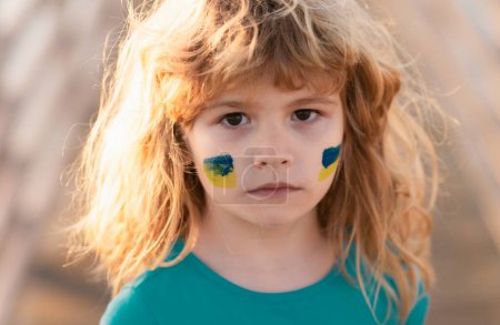 Téléchargez les photos : Signes du drapeau ukrainien sur la joue de l'enfant. Jeune enfant dans une manifestation avec le drapeau ukrainien. Les enfants protestent - en image libre de droit