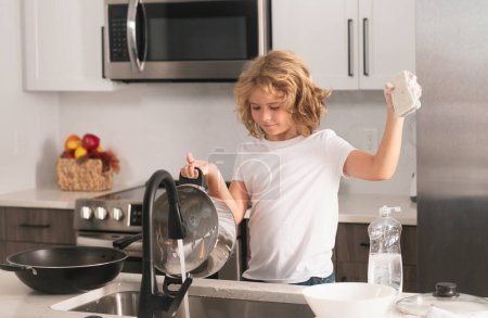 Téléchargez les photos : Lave-vaisselle enfant avec eau et savon près de l'évier dans la cuisine - en image libre de droit