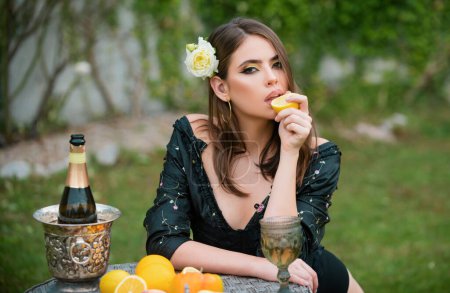 Foto de Sexy hermosa mujer joven comiendo naranja, verduras y frutas, contra el fondo del parque verde de verano - Imagen libre de derechos