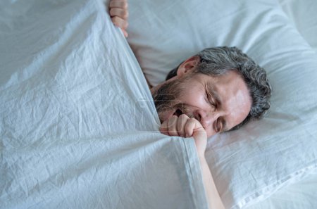 Photo for Man yawning in bed. Yawn and nap. Snore sleepy napping yawning wake up. Mattress pillow bed. Slumber overslept. Morning yawning . Hispanic man yawning in bedroom. Close up bearded man in cozy bed - Royalty Free Image