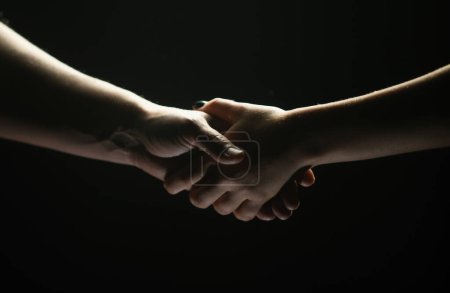 Photo for Hands gesturing on black background. Giving a helping hand. Support and help, agreement. Hands of two people of rescue. Helping hand outstretched for salvation. Handshake between the two partners - Royalty Free Image