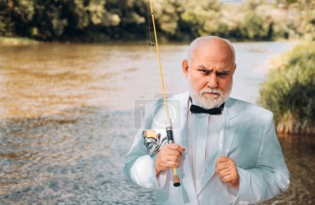 Photo for Portrait of senior businessman fishing. Excited mature man fisherman in suit with fishing rod, spinning reel on river - Royalty Free Image