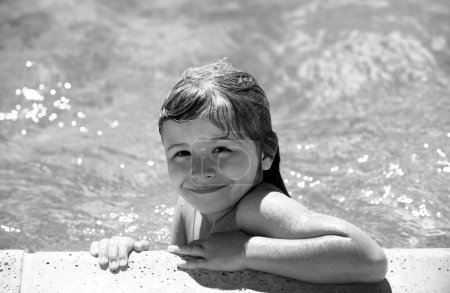 Téléchargez les photos : Détendez-vous dans la piscine d'été. Petit garçon jouant dans la piscine extérieure dans l'eau pendant les vacances d'été. Enfant apprenant à nager dans la piscine extérieure - en image libre de droit