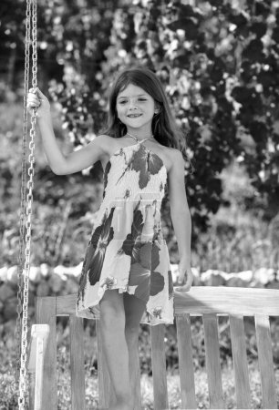Téléchargez les photos : Jolie petite fille sur une balançoire. Enfant souriant jouant dehors en été. Des enfants heureux qui se balancent au parc. Enfant heureux s'amuser à l'extérieur - en image libre de droit
