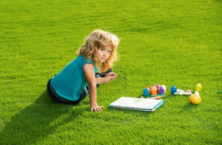 Photo for Portrait of smiling happy kid enjoying art and craft drawing in backyard or spring park. Children drawing draw with pencils outdoor. Children hobby, happy childhood - Royalty Free Image