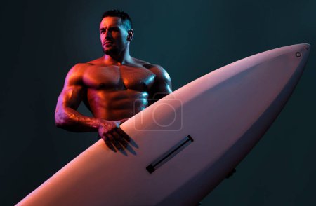 Téléchargez les photos : Surfeur sexy avec une planche de surf. Portrait d'athlète séduisant avec planche de serf. Plage masculine loisirs, vacances d'été - en image libre de droit