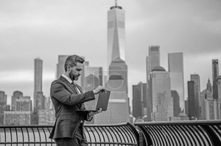 Photo for Businessman with laptop in New York City. Financial Manhattan. Office worker hold laptop against cityscape in NYC. Business man using laptop outdoor. Office work on laptop. Millennial freelancer - Royalty Free Image