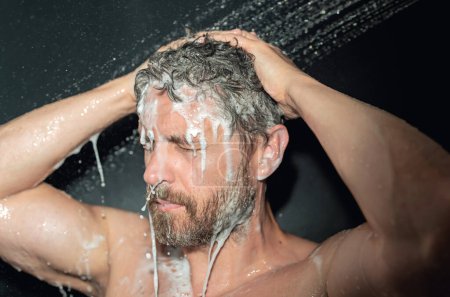 Mann wäscht Haare, Nahaufnahme Porträt. Badedusche waschen Haarkopf im Badezimmer. Männliches Modell wäscht Haare in der Dusche. Mann unter der Dusche. Kerlduschen, Haarpflege. Männliches Shampoo und Haarwaschkonzept