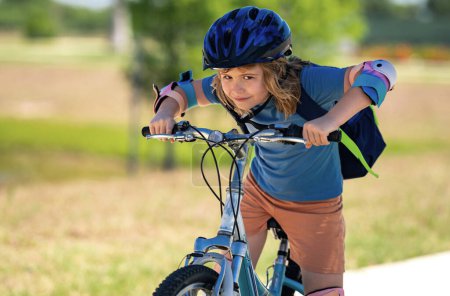 Photo for Boy in a helmet riding bike. Boy in safety helmet riding bike in city park. Child first bike. Kid outdoors summer activities. Kid on bicycle. Little child riding bike in summer park on a driveway - Royalty Free Image