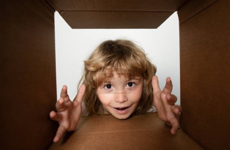 Photo for Child looking inside cardboard box, bottom view. Delivering your purchase. Kids celebrate birthday. Birthday gift. Parcel packaging or unpacking concept - Royalty Free Image