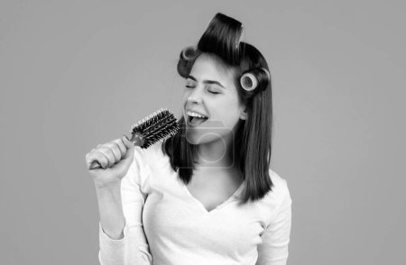 Funny woman singing with comb. Beautiful young woman holding healthy and shiny hair, studio. Closeup on young woman combing hair