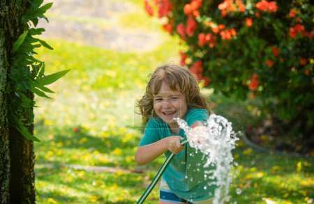 Foto de Niño jugando en el jardín, vierte de la manguera, hace una lluvia. Concepto de infancia feliz - Imagen libre de derechos