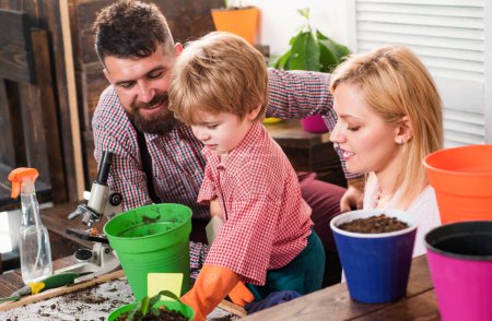 Photo for Happy family of three having fun together. Cheerful parents playing with son growing plant in pot. Father mother and child playing together - Royalty Free Image