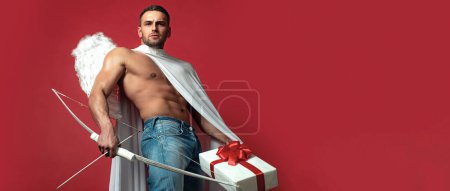 Foto de Valentines Day banner. Sexy guy with angels wings. Cupid. Amour. February 14. Arrow of love. Isolated on red. Banner flyer template for advertising for header design - Imagen libre de derechos