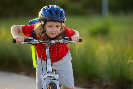 Little kid boy ride a bike in the park. Kid cycling on bicycle. Happy smiling child in helmet riding a bike. Boy start to ride a bicycle. Sporty kid bike riding on bikeway. Kids bike