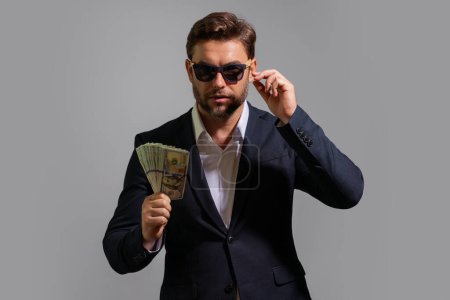 Photo for Business man hold money on gray studio isolated background. Rich man in suit with money dollar bills. Successful businessman with dollar banknotes. Rich millionaire in suit holding money - Royalty Free Image
