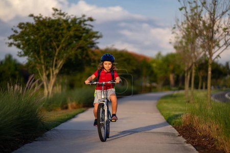 Téléchargez les photos : Enfant à vélo dans un casque. Enfant vélo d'équitation dans un casque de protection. Sécurité enfants sport et activité. Joyeux garçon en vélo dans le parc d'été. Casque de vélo, sécurité vélo, accessoires cyclistes - en image libre de droit