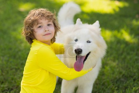 Foto de Retrato de niño y perro. Chico jugando con Husky. Un perro abrazado en el parque. El chico abraza a un perro en el parque. Mascotas y la infancia. Niños Estilo de vida con perros. Chico juega con un perro husky - Imagen libre de derechos