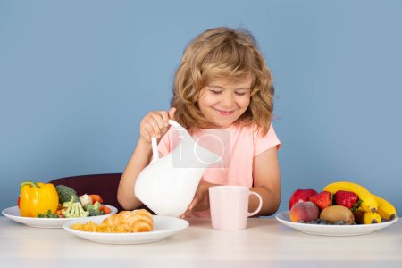 Téléchargez les photos : Petit déjeuner sain pour les enfants. Enfant versant du lait, portrait isolé en studio. Boisson pour enfants lait laitier - en image libre de droit