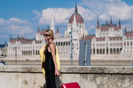 Foto de Mujer turista en vestido de moda con maleta caminando por la calle. Chica estudiante viajero retrato al aire libre. Turista mujer teniendo viaje de vacaciones - Imagen libre de derechos