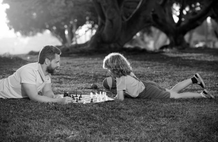 Téléchargez les photos : Father and son playing chess spending time together outdoor. Games and entertainment for children. Family concept - en image libre de droit