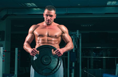 Foto de Powerlifter con disco de peso en gimnasio deportivo. Culturista con disco pesado entrena sus bíceps - Imagen libre de derechos