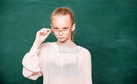 Photo for Funny teen student. Young girl standing against blackboard. Portrait of modern happy teenager school girl. College student at campus - Royalty Free Image