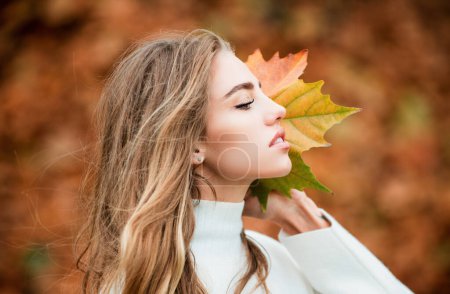 Foto de Retrato de una joven alegre con hojas de otoño frente al follaje - Imagen libre de derechos