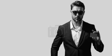 Studio portrait of man with a credit card on gray isolated background. Money management and credit score. Rewards programs. Credit limits. Banner for header, copy space. Poster for web design