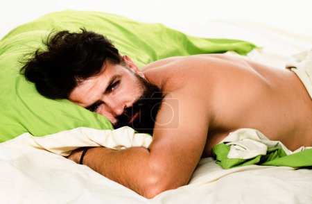 Téléchargez les photos : Attrayant barbu gars tenant dans les mains oreiller dans le lit. Garçon dormant et rêvant. L'homme dort seul au lit - en image libre de droit