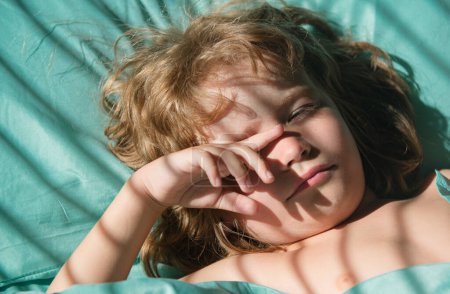 Téléchargez les photos : Garçon enfants dormir, enfant couché sur un lit tout en dormant dans une chambre lumineuse - en image libre de droit