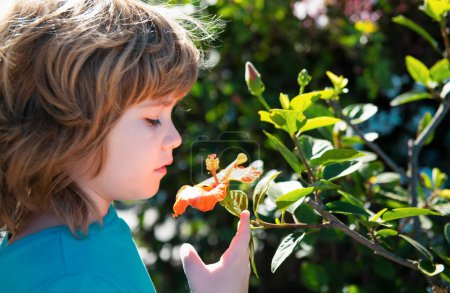 Téléchargez les photos : Garçon de printemps dans le parc naturel. Enfant avec fleur en plein air. Jardin fleuri - en image libre de droit