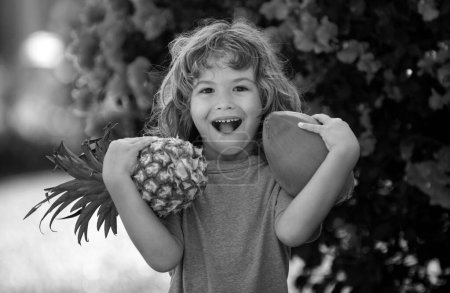 Photo for Cute kid with pineapple and coconut at tropical garden. Fresh tropical fruits for kids. Healthy lifestyle with fresh organic tropical fruits - Royalty Free Image