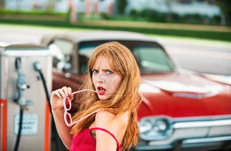 Photo for Sexy woman at gas station. Elegant lady against red retro automobile - Royalty Free Image