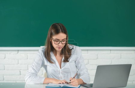 Photo for Student preparing exam and learning lessons in school classroom. Female freelancer or a student with laptop computer - Royalty Free Image